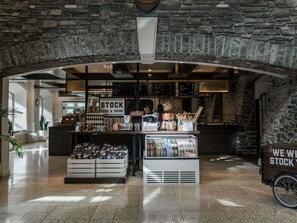 A stock food and drink counter with a stone archway, a refrigerated display, and a delivery cart.