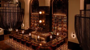 A bar area with a counter, stools, and shelves of bottles.