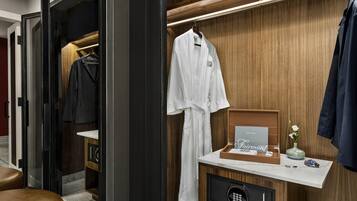 A modern bathroom with a wooden vanity, a robe hanging, and a safe.