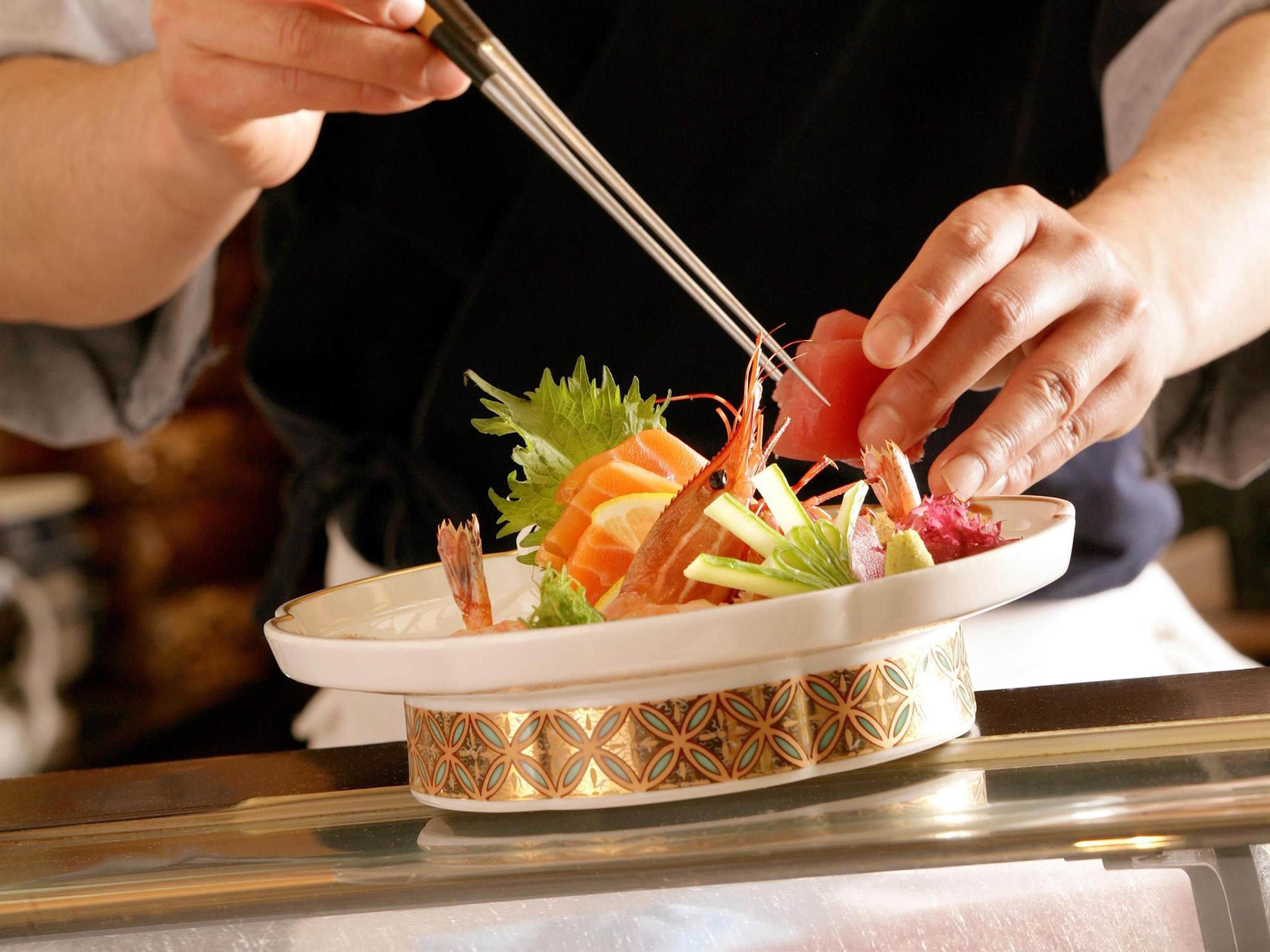 A person using chopsticks to pick up food from a plate.
