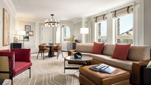 A modern living room with a sofa, ottoman, chairs, a coffee table, and a dining area with chairs and a table.