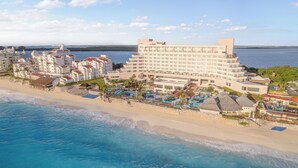 Um hotel à beira-mar com vários edifícios, praia e área de piscina.