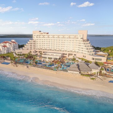 A coastal hotel with multiple buildings, a beachfront, and a swimming pool area.