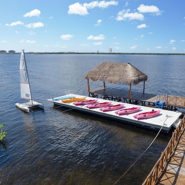 A dock with a thatched-roof structure and a boat with kayaks.