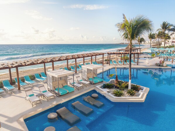 A resort pool area with lounge chairs and a view of the ocean.