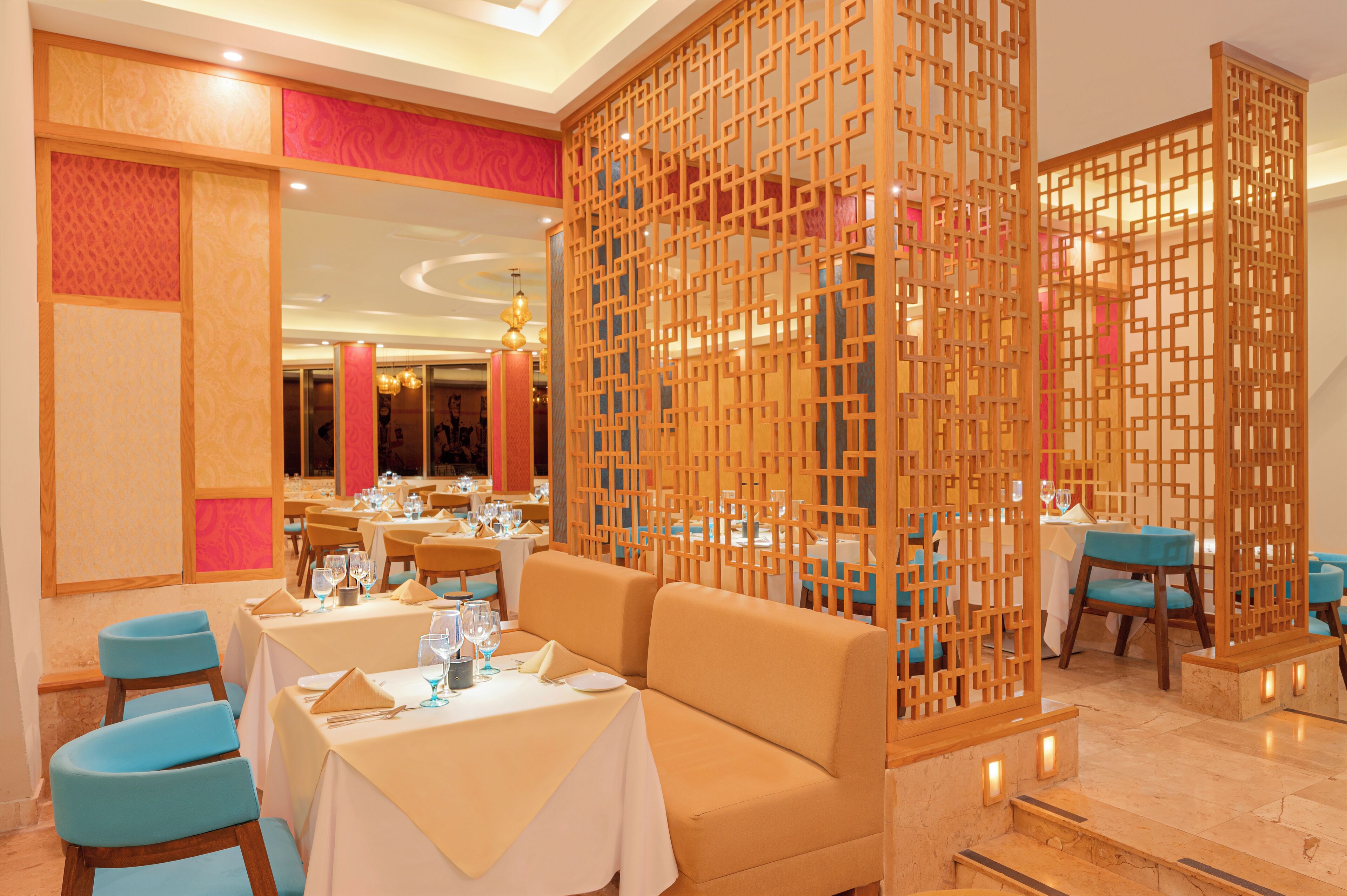 A dining area with tables set for a meal, a sofa, and a decorative wooden partition.