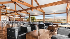 A spacious restaurant with high ceilings, wooden beams, and large windows offering a view of the landscape. - Columbia River Hotel and Conference Center, an Ascend Collection Hotel (The Dalles)