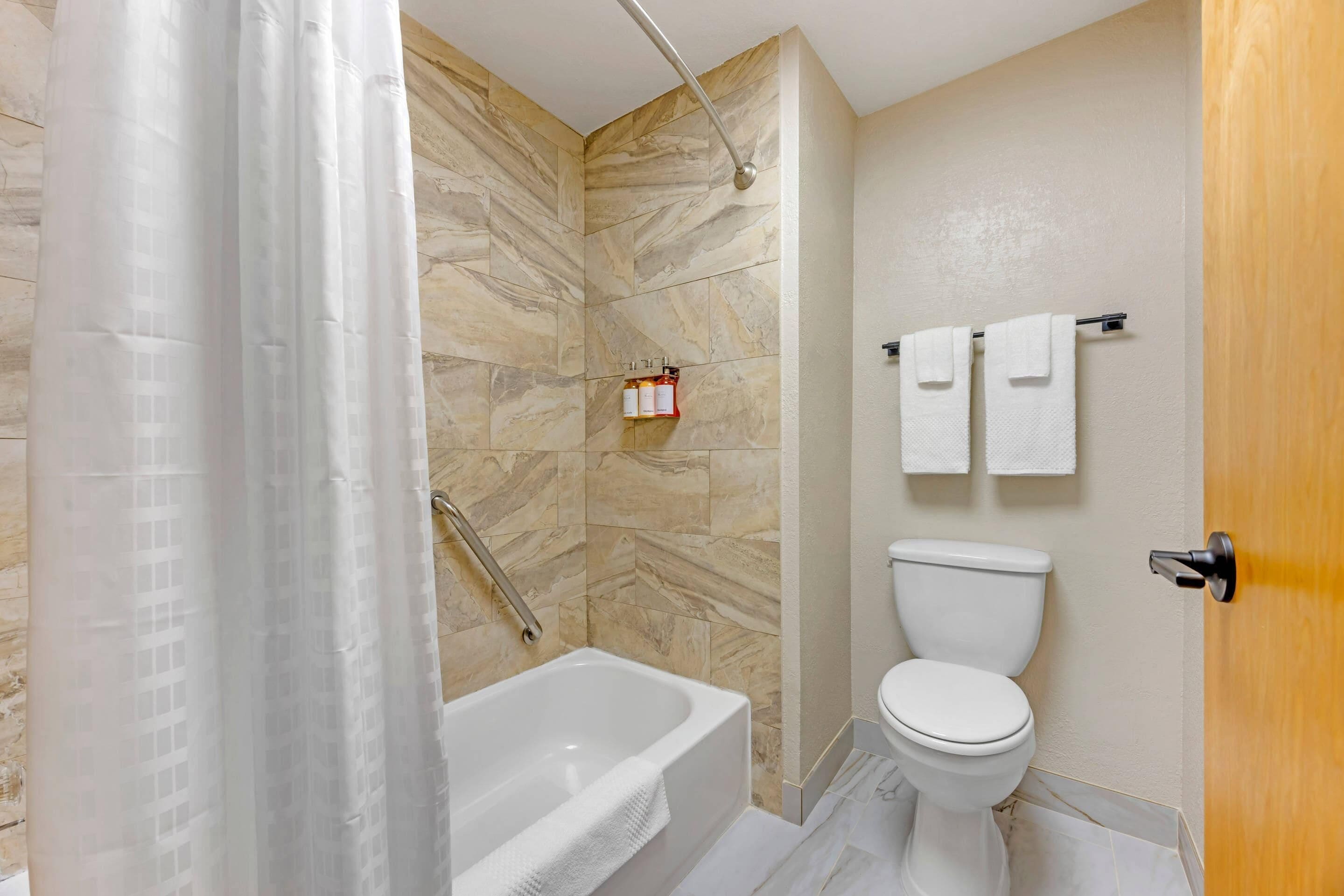 Ein Badezimmer mit Badewanne, Toilette und Duschvorhang.