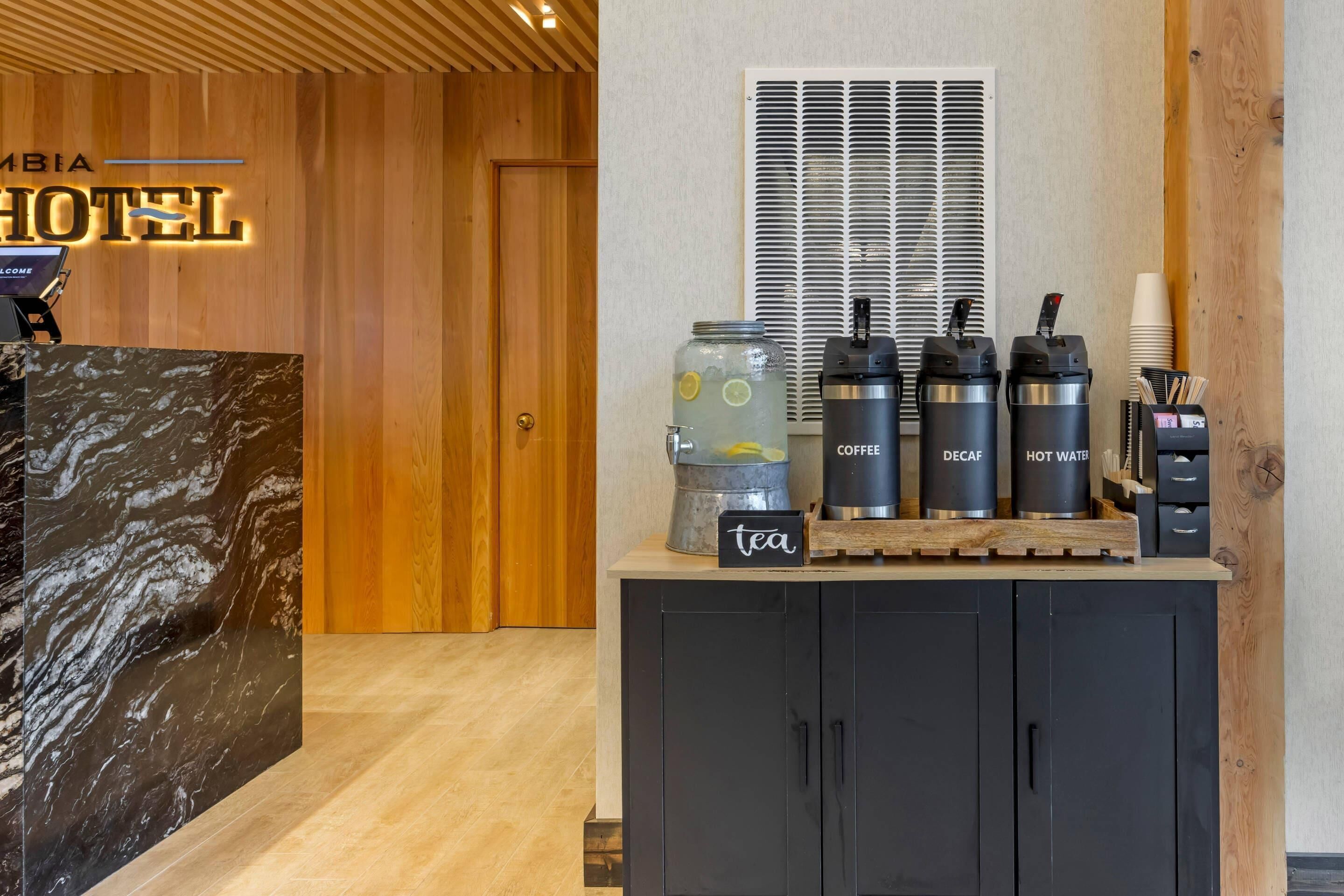 A hotel reception area with a marble counter, a coffee station, and a tea station.