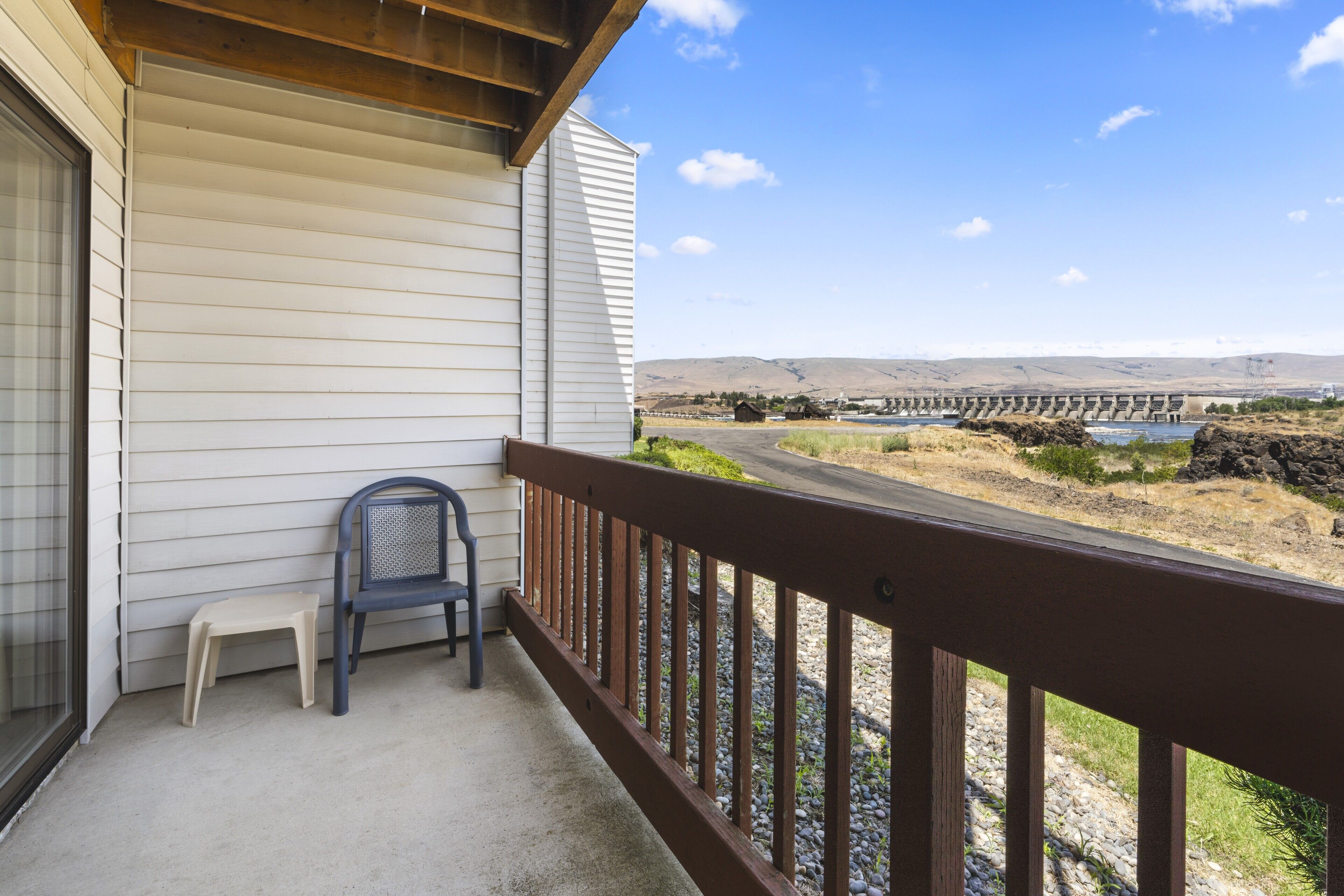 A balcony with a view of a dam and hills.