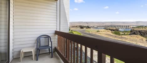 A balcony with a view of a dam and hills.