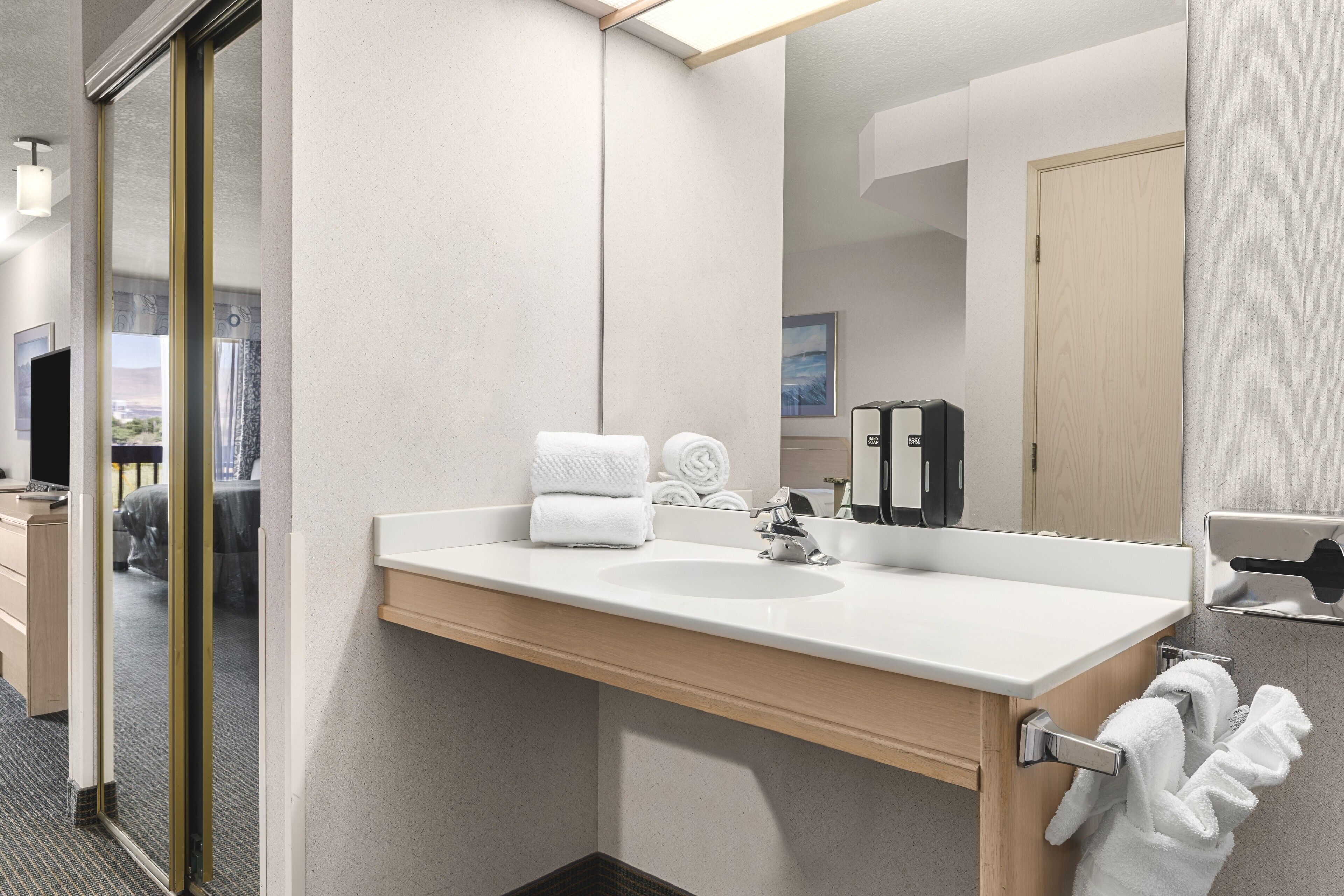 Un bany modern amb un mirall gran, un lavabo blanc i una barra de tovalloles.