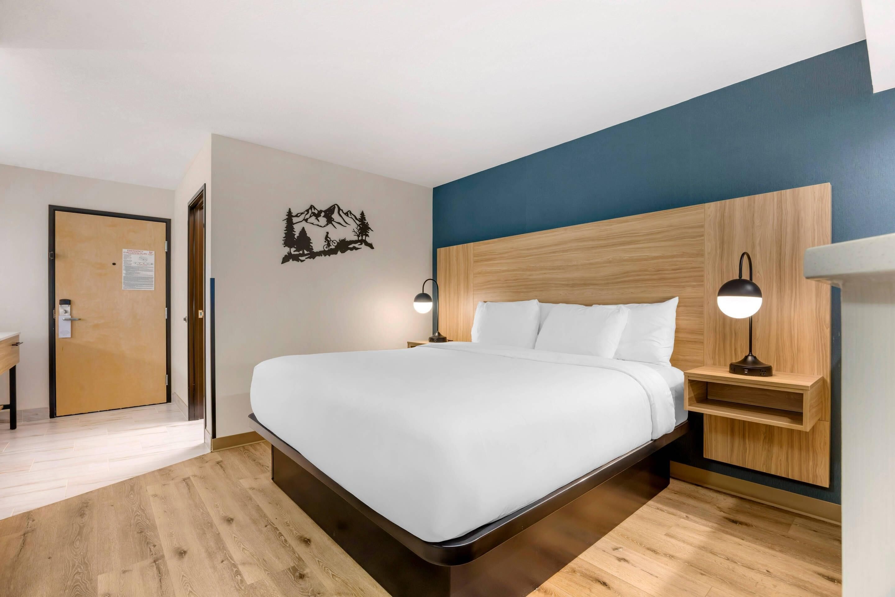 A modern hotel room with a large bed, wooden headboard, and bedside tables with lamps.