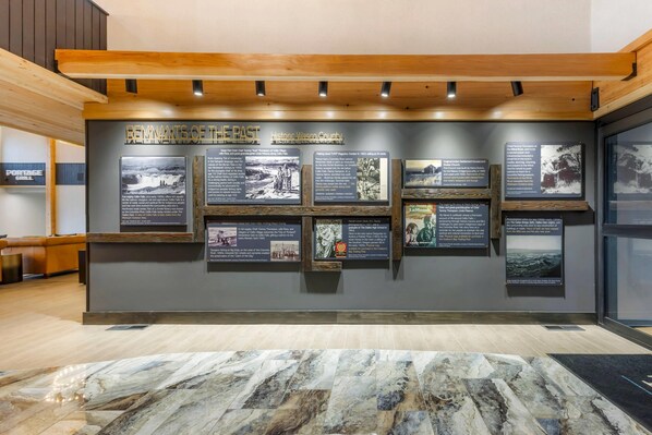 A wall with multiple informational panels titled "REMINANTS OF THE PAST" in a modern interior space with wooden beams and a marble floor.