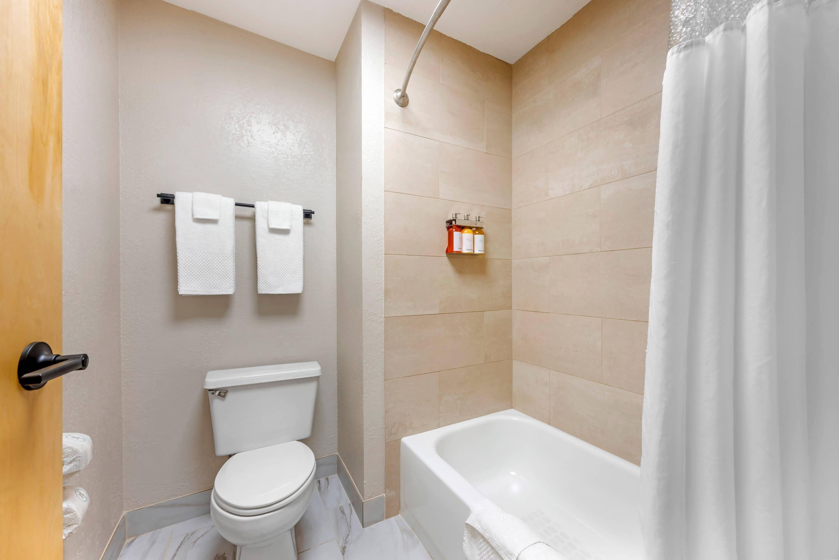 A bathroom with a toilet, a bathtub, and a shower curtain.