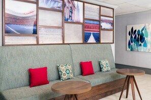 A modern interior with a grey patterned sofa, red cushions, and a wooden coffee table. - Hampton Inn Buffalo-Airport / Galleria Mall (Buffalo)