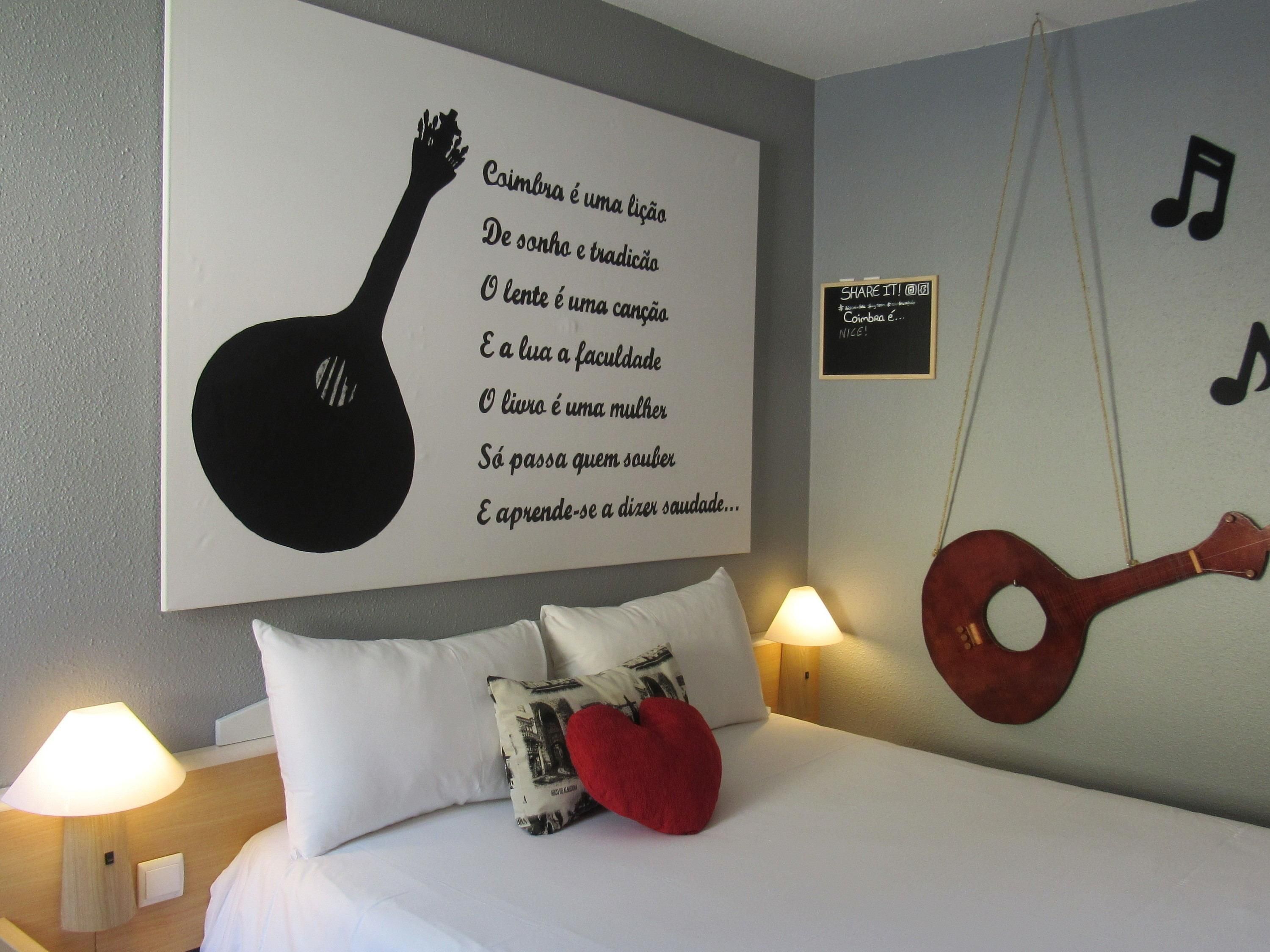 A bedroom with a bed, pillows, a wall with a guitar and a guitar-shaped text, and a small sign with a musical note.