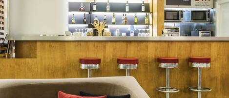 A modern bar area with a minibar, stools, and a sign indicating 24-hour meal service.