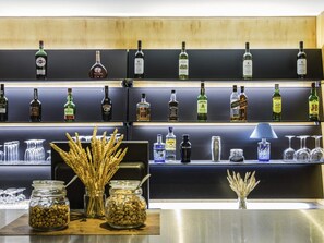 A bar area with shelves of liquor bottles, glasses, and jars of nuts. - ibis Coimbra Centro (Coimbra)