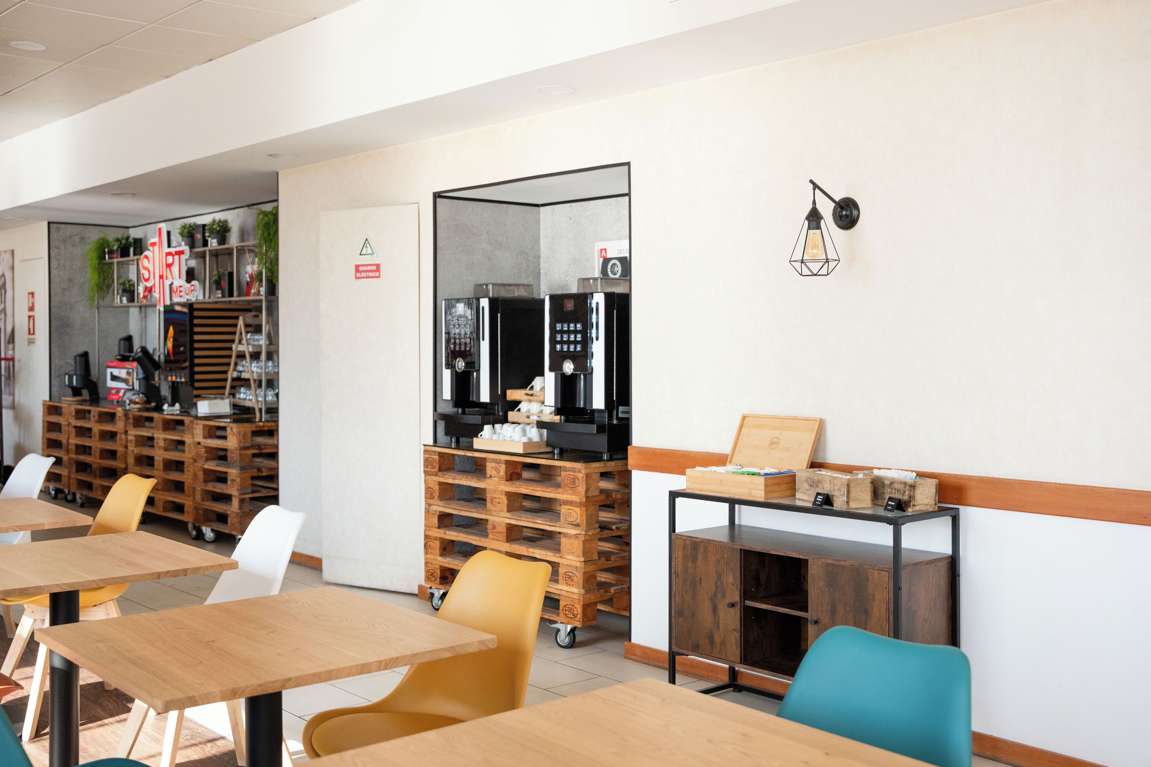 A modern cafe with wooden tables and chairs, a coffee machine, and a menu board.