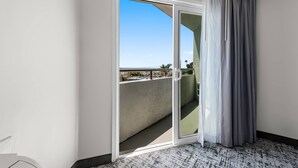 A room with a sliding glass door leading to a balcony with a clear view of the sky and distant landscape. - Quality Inn & Suites Hermosa Beach (Hermosa Beach)