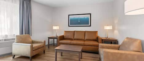 A modern living room with a sofa, two armchairs, a coffee table, and two side tables with lamps.