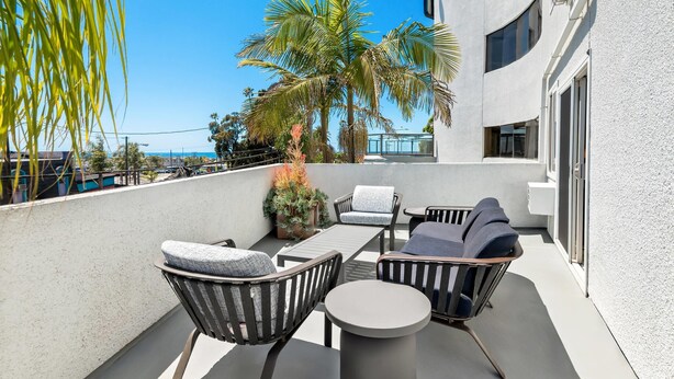 A balcony with outdoor furniture, palm trees, and a view of the ocean. - Quality Inn & Suites Hermosa Beach (Hermosa Beach)