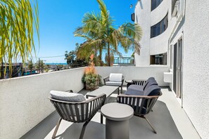A balcony with outdoor furniture, palm trees, and a view of the ocean. - Quality Inn & Suites Hermosa Beach (Hermosa Beach)