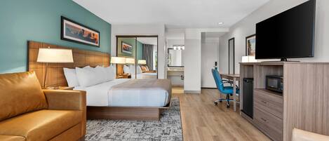 Ein modernes Hotelzimmer mit Bett, Sofa, Schreibtisch, Fernseher und Mikrowelle.