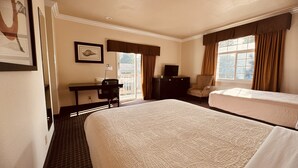Een hotelkamer met twee bedden, een bureau met stoel, een televisie en een raam met gordijnen.