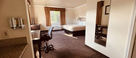 Een hotelkamer met een bed, bureau, stoel en spiegel.