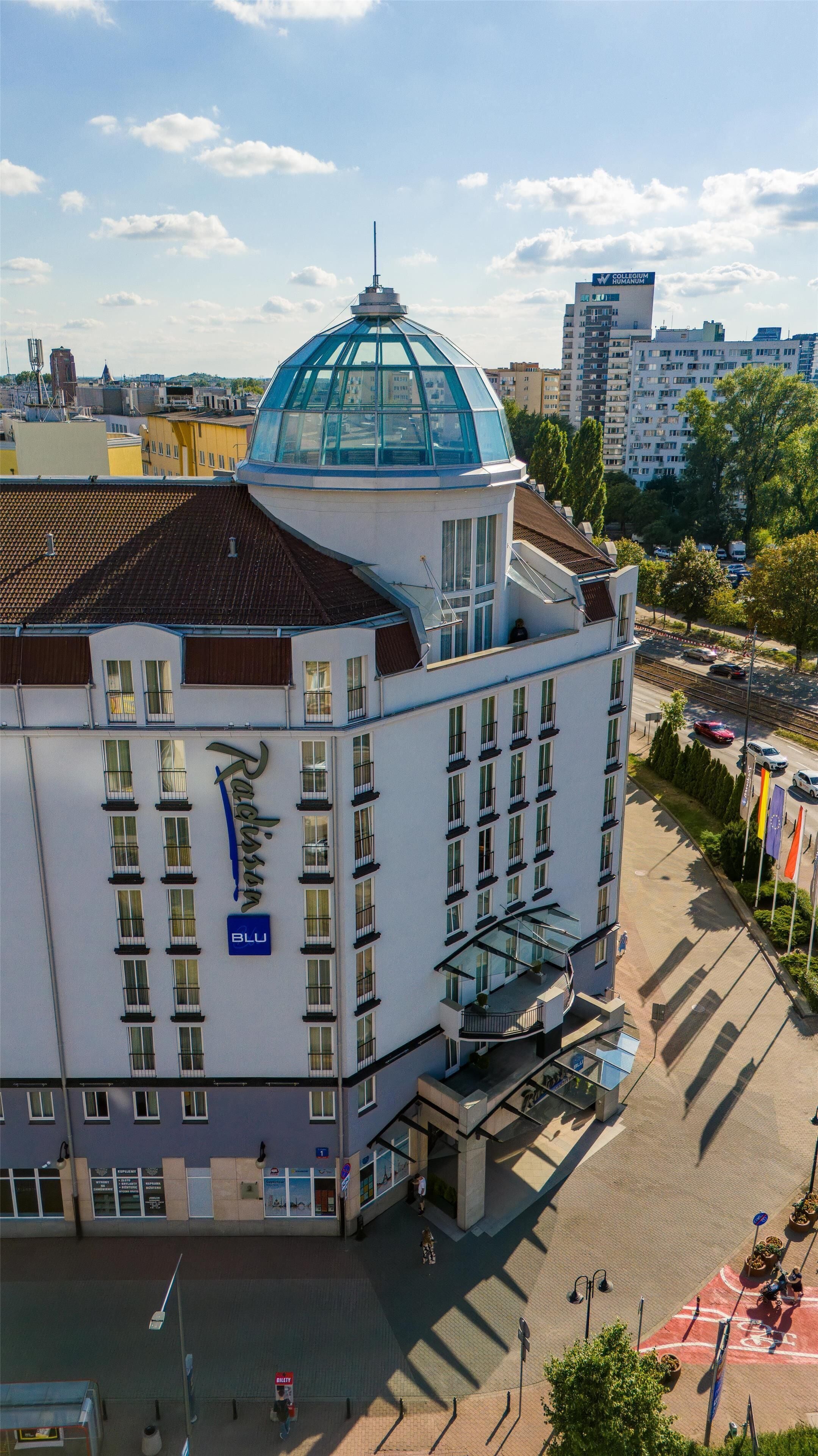 Un edificio de varios pisos con una cúpula azul distintiva, ventanas amplias y un letrero que indica que es un hotel.