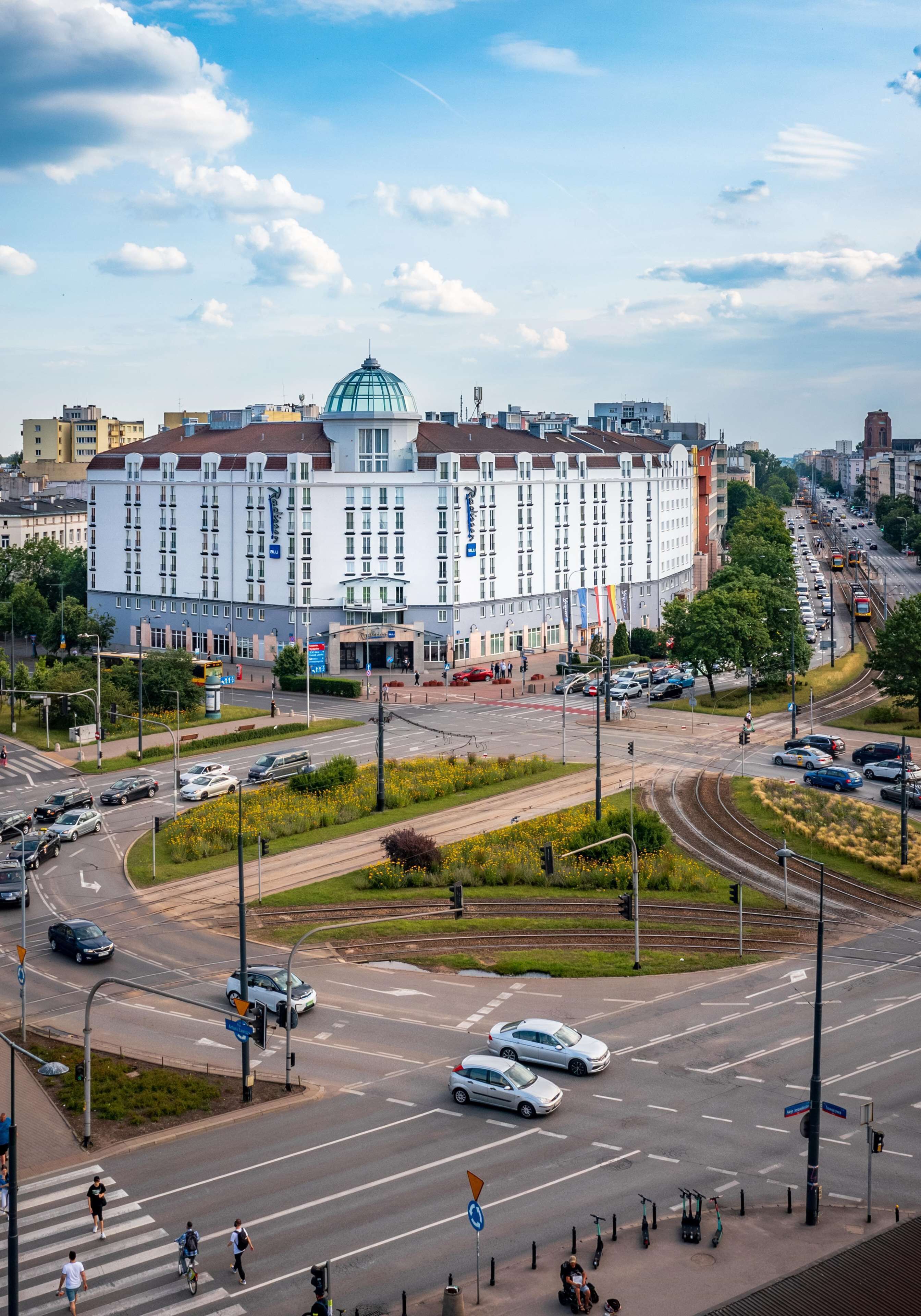 Un edificio grande con una cúpula, rodeado por una concurrida intersección con varios carriles y semáforos.