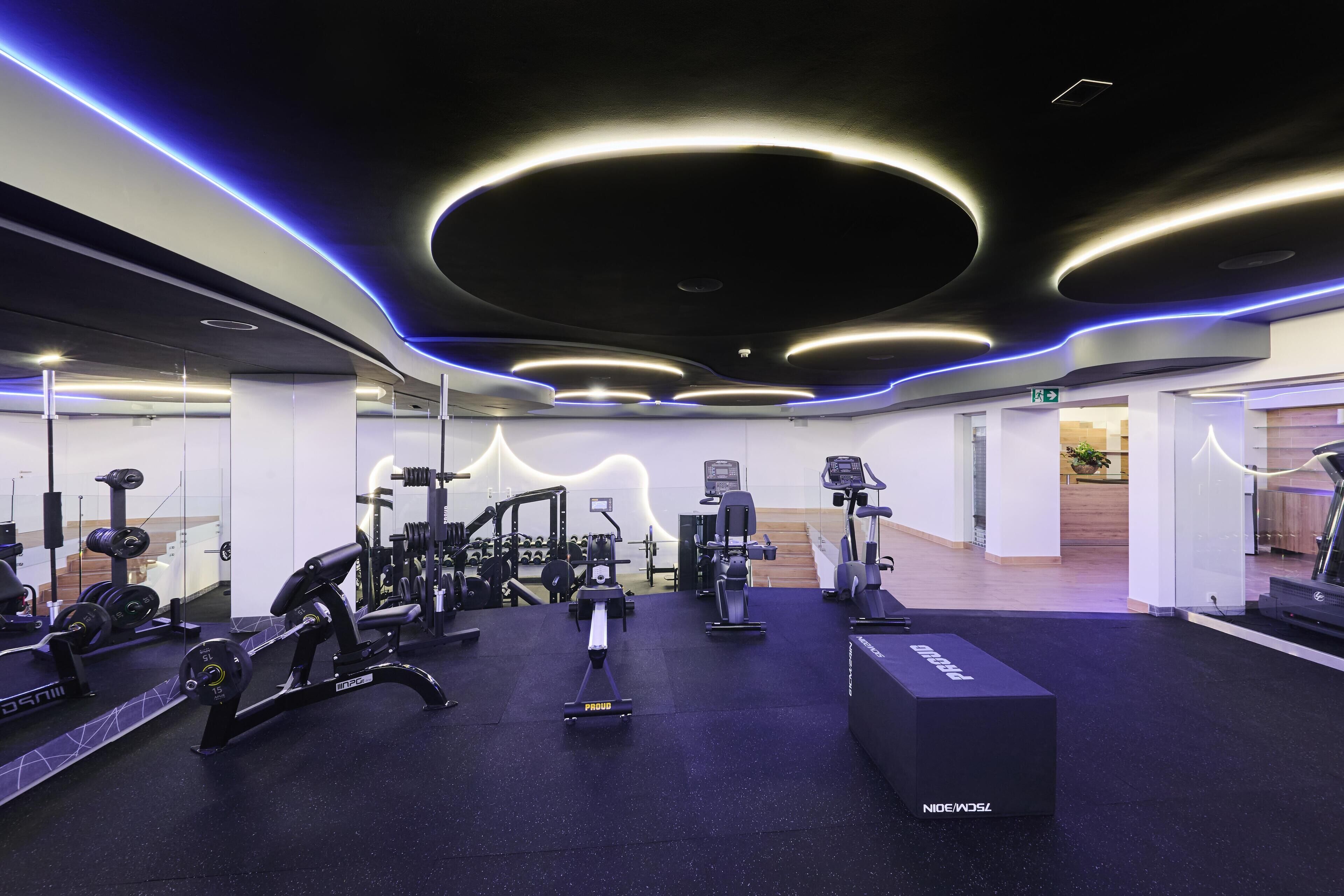 A modern gym with various exercise equipment, including a rowing machine, dumbbells, and weight benches.