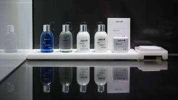 Presentación de varios productos de cuidado corporal Redissona, incluyendo gel de ducha, champú esencial, acondicionador intensivo, loción corporal, gorro de ducha y un neceser.