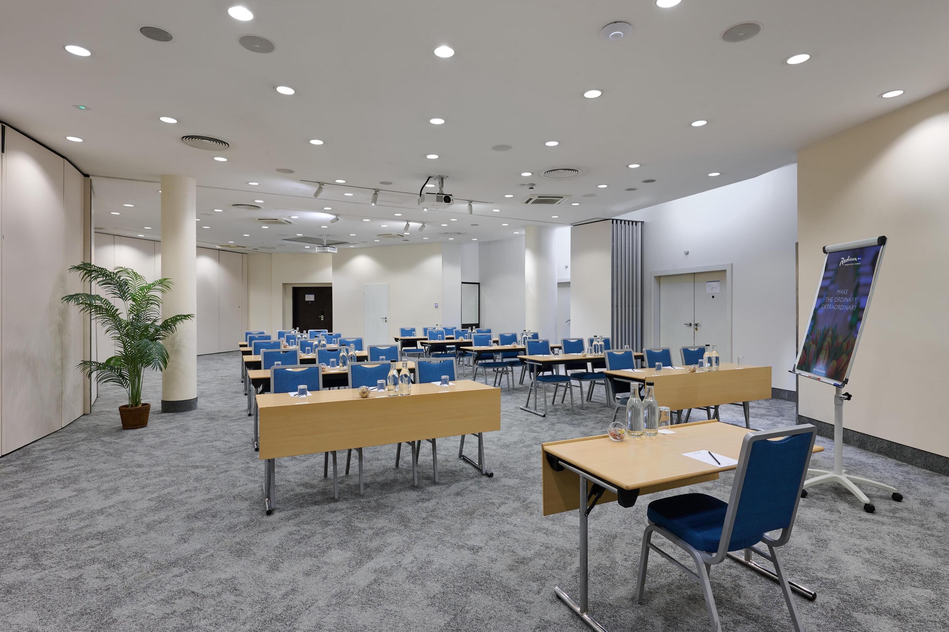 A conference room with multiple tables and chairs, a projector, and a presentation screen.