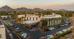 A hotel with a curved facade, a parking lot, and a mountainous backdrop. - Embassy Suites by Hilton Phoenix Biltmore (Phoenix)