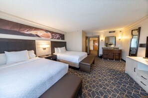 A hotel room with two beds, a desk, a bench, a bathroom with a mirror, and a patterned carpet. - Embassy Suites by Hilton Phoenix Biltmore (Phoenix)