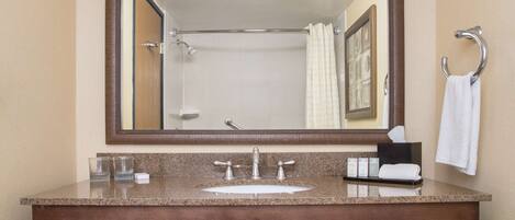 Une salle de bain avec un grand miroir, deux lavabos et un porte-serviettes.