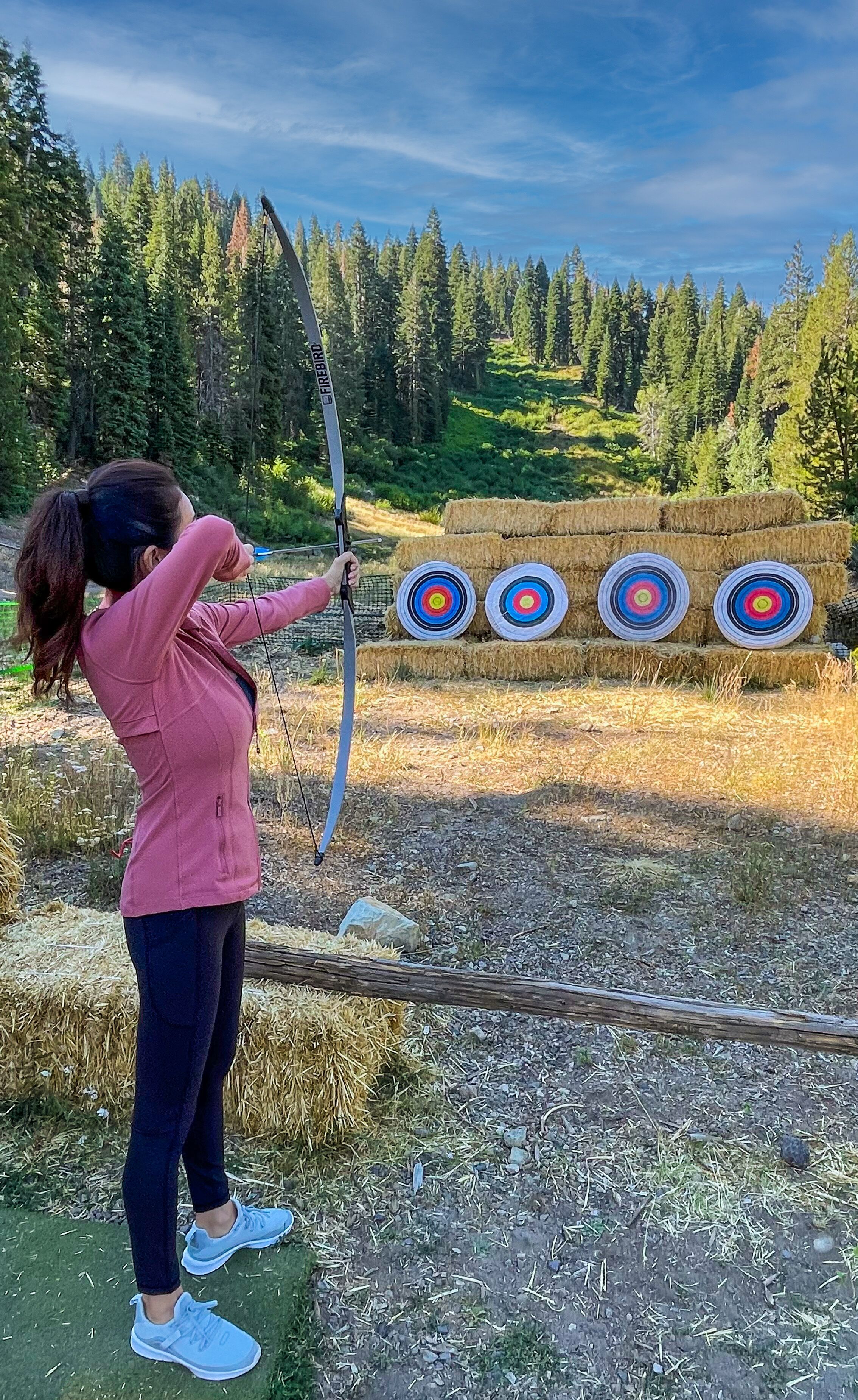 A person aiming a bow at a target with concentric circles.