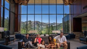 Una familia jugando ajedrez en un amplio salón con grandes ventanales que ofrecen vistas a la montaña.