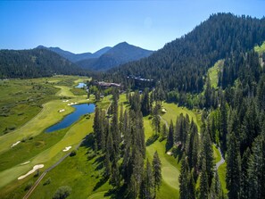 A golf course with a clubhouse, surrounded by dense forests and mountains. - Everline Resort and Spa, Lake Tahoe (Olympic Valley)