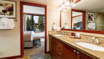 A bathroom with two sinks, a large mirror, and a window with a view of trees.