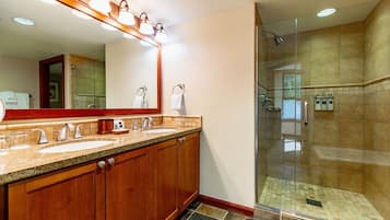 A bathroom with a double sink vanity, a large mirror, and a glass-enclosed shower area.
