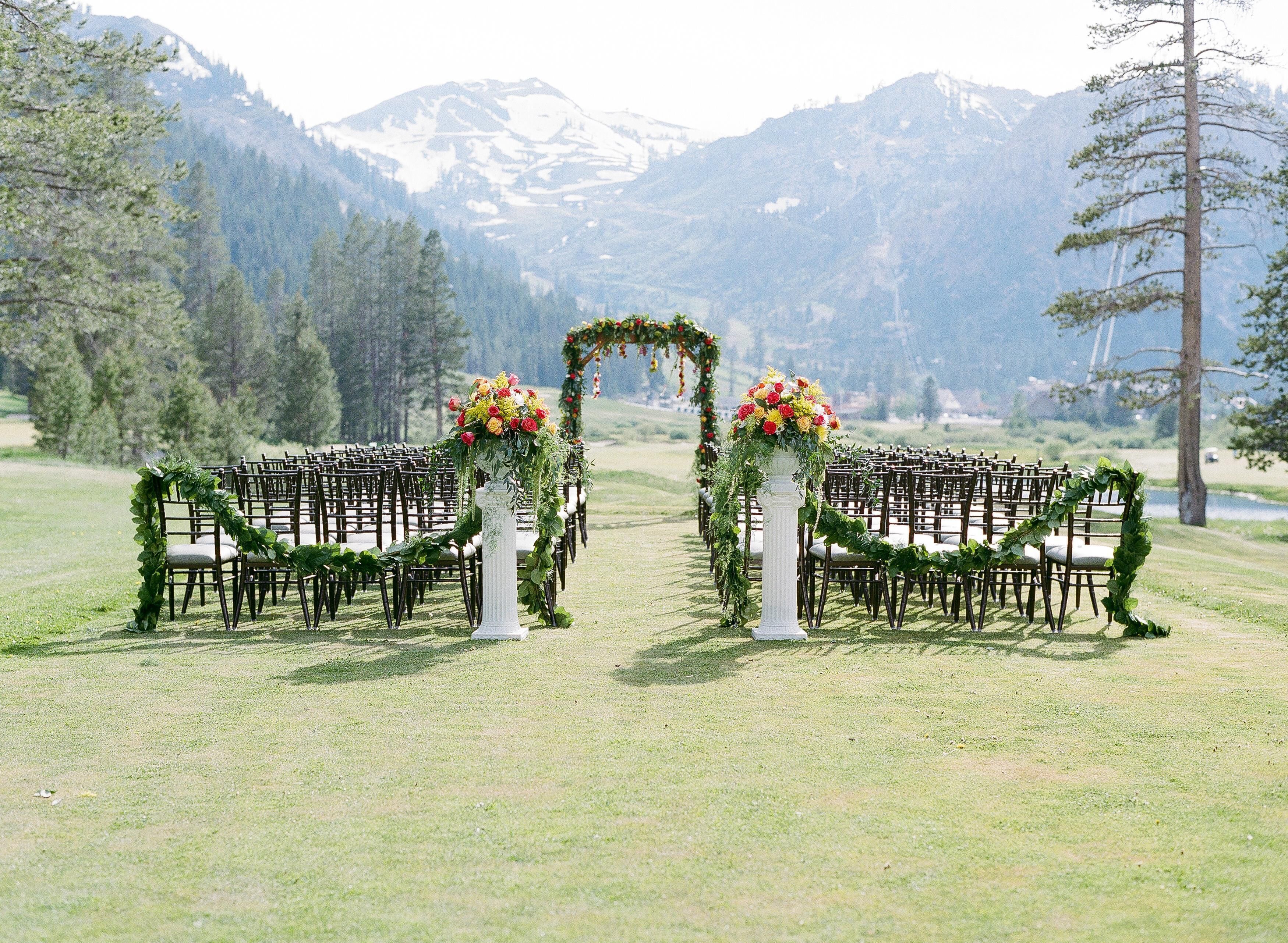 Un salón de bodas al aire libre con hileras de sillas y decoración floral.