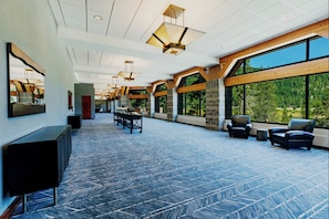 A spacious lobby with a high ceiling, large windows offering a view of the outdoors, and a reception desk.