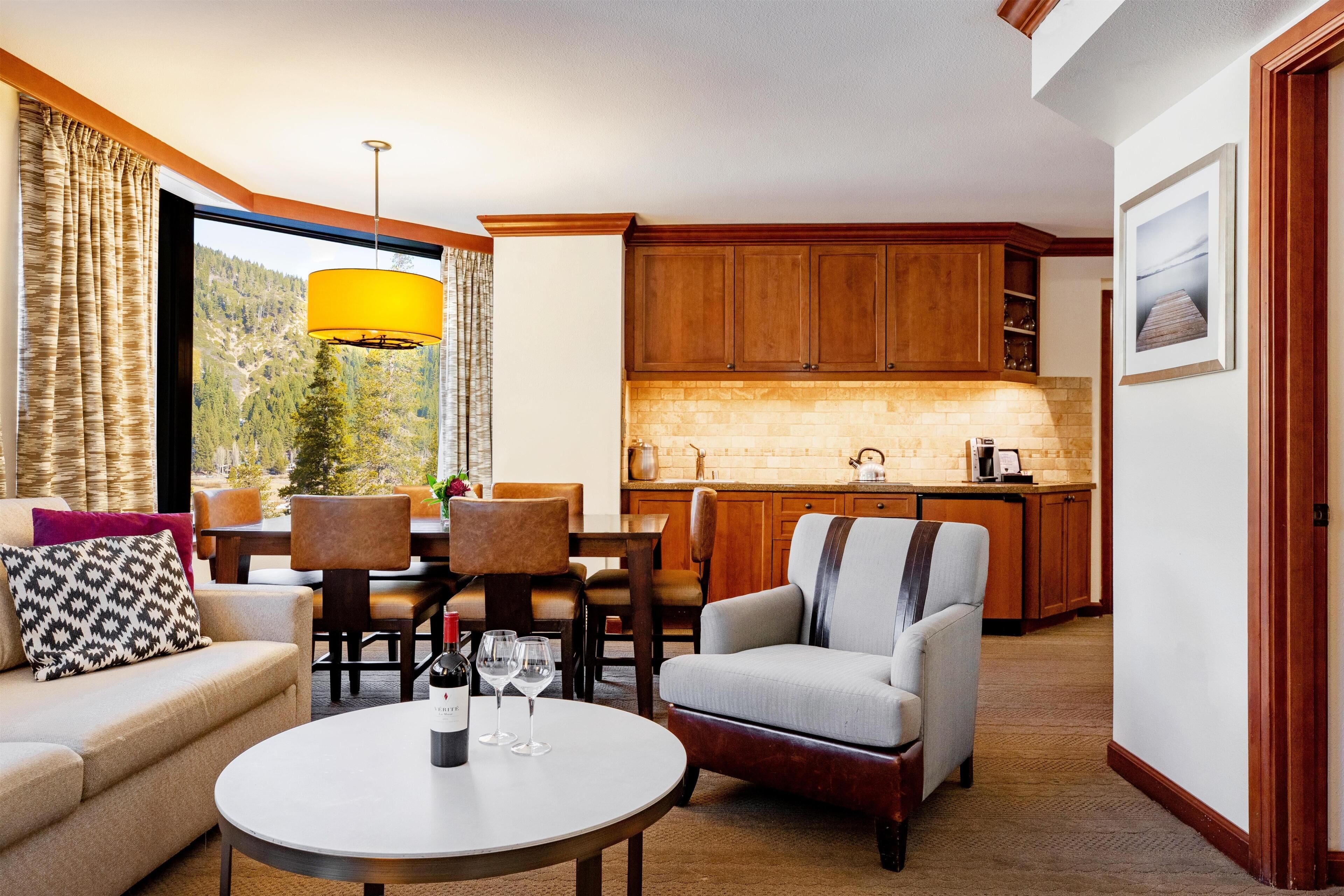 Una sala de estar con sofá, sillones, una mesa de comedor y una cocina al fondo.