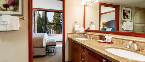 A bathroom with a large mirror, two sinks, and a window with a view of trees.