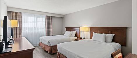 Ein Hotelzimmer mit zwei Betten, einem Schreibtisch mit Lampe und einem Fernseher.
