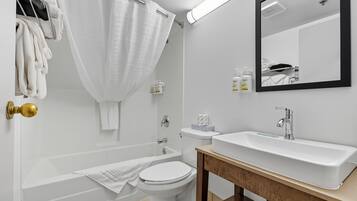 Een moderne badkamer met een bad, toilet en wastafel.